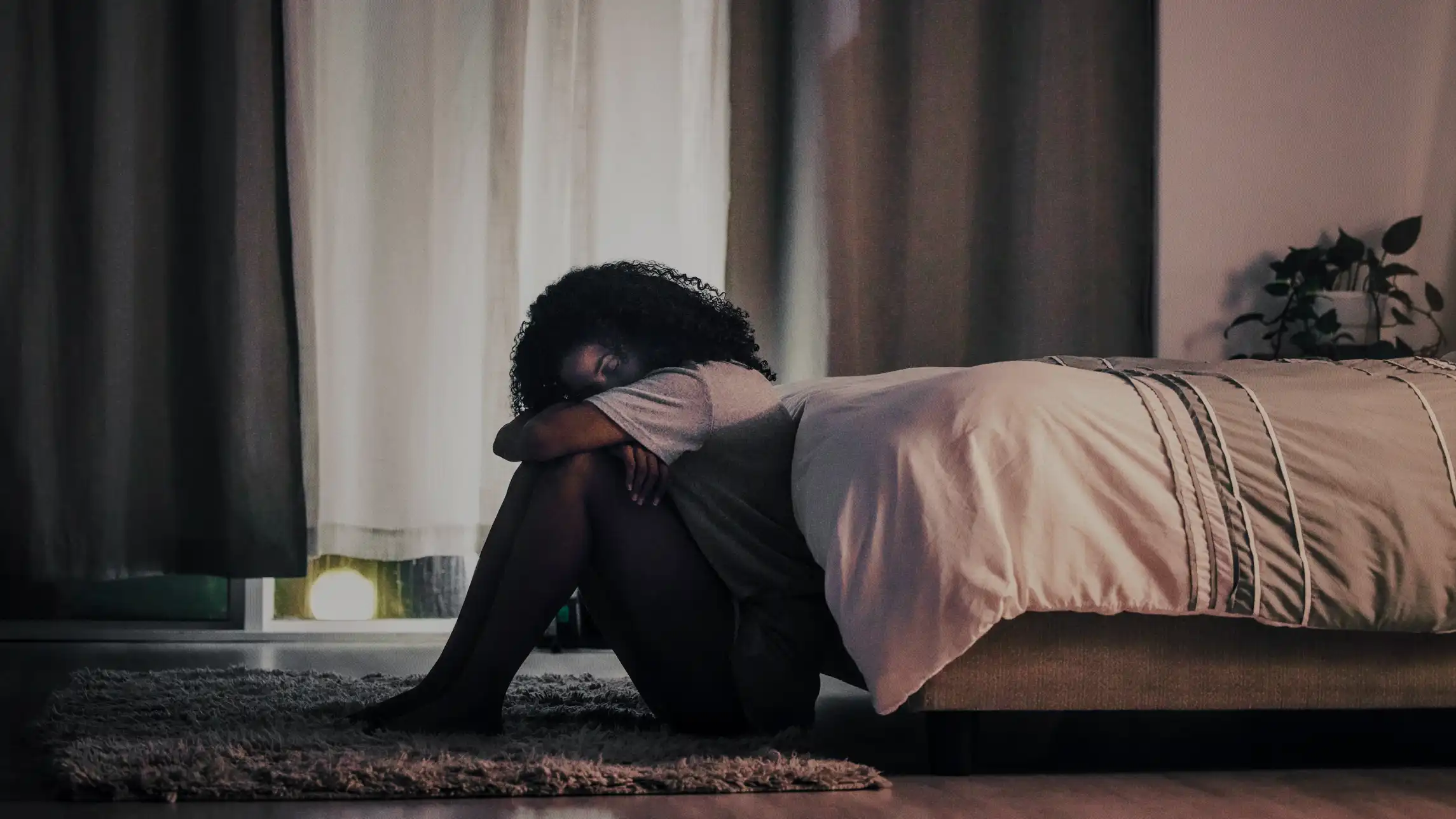 Woman curled up sad on the floor of bedroom