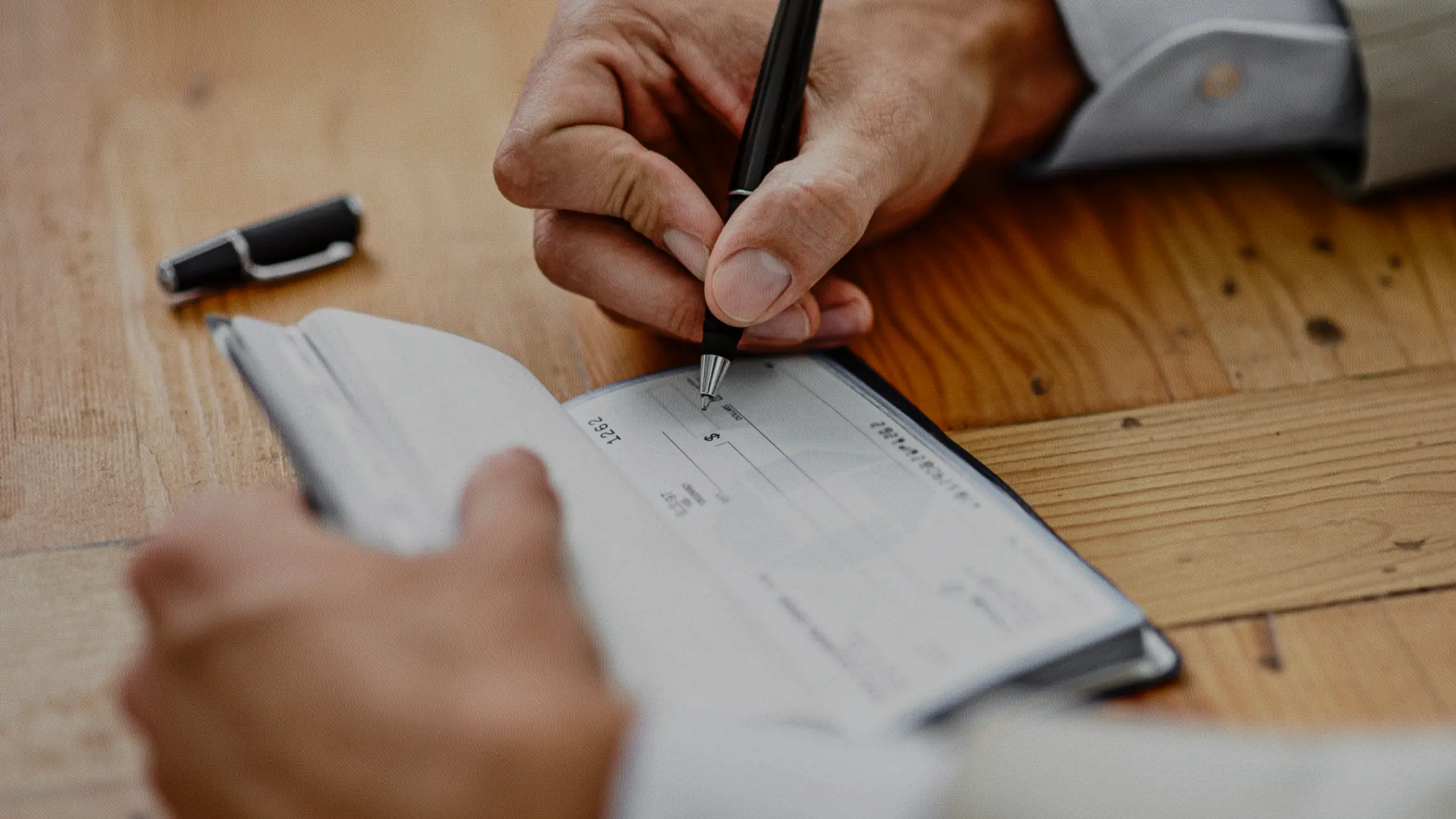 Person writing a check with ballpoint pen