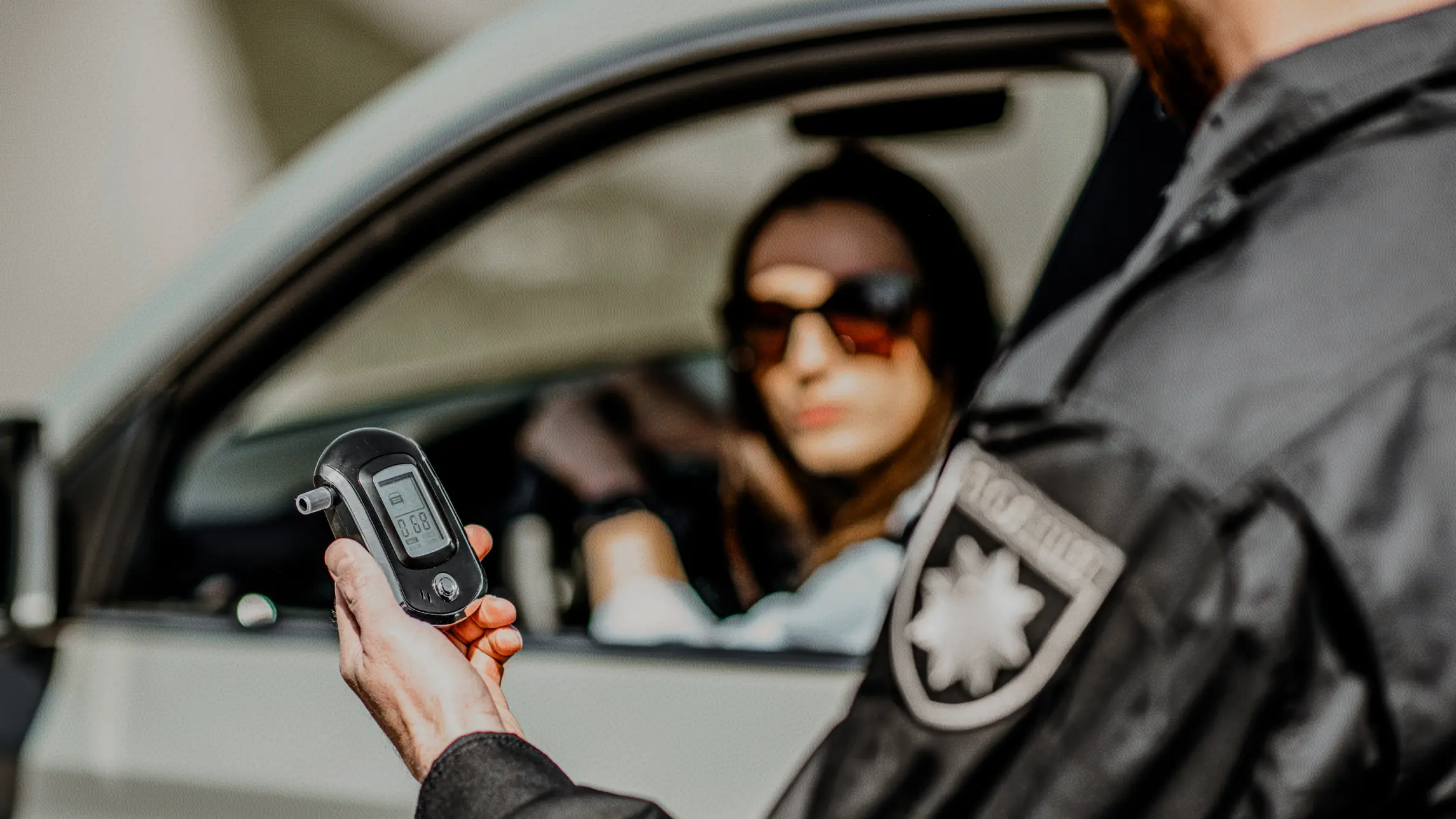 Police looking at breathalyzer at a traffic stop with woman in car