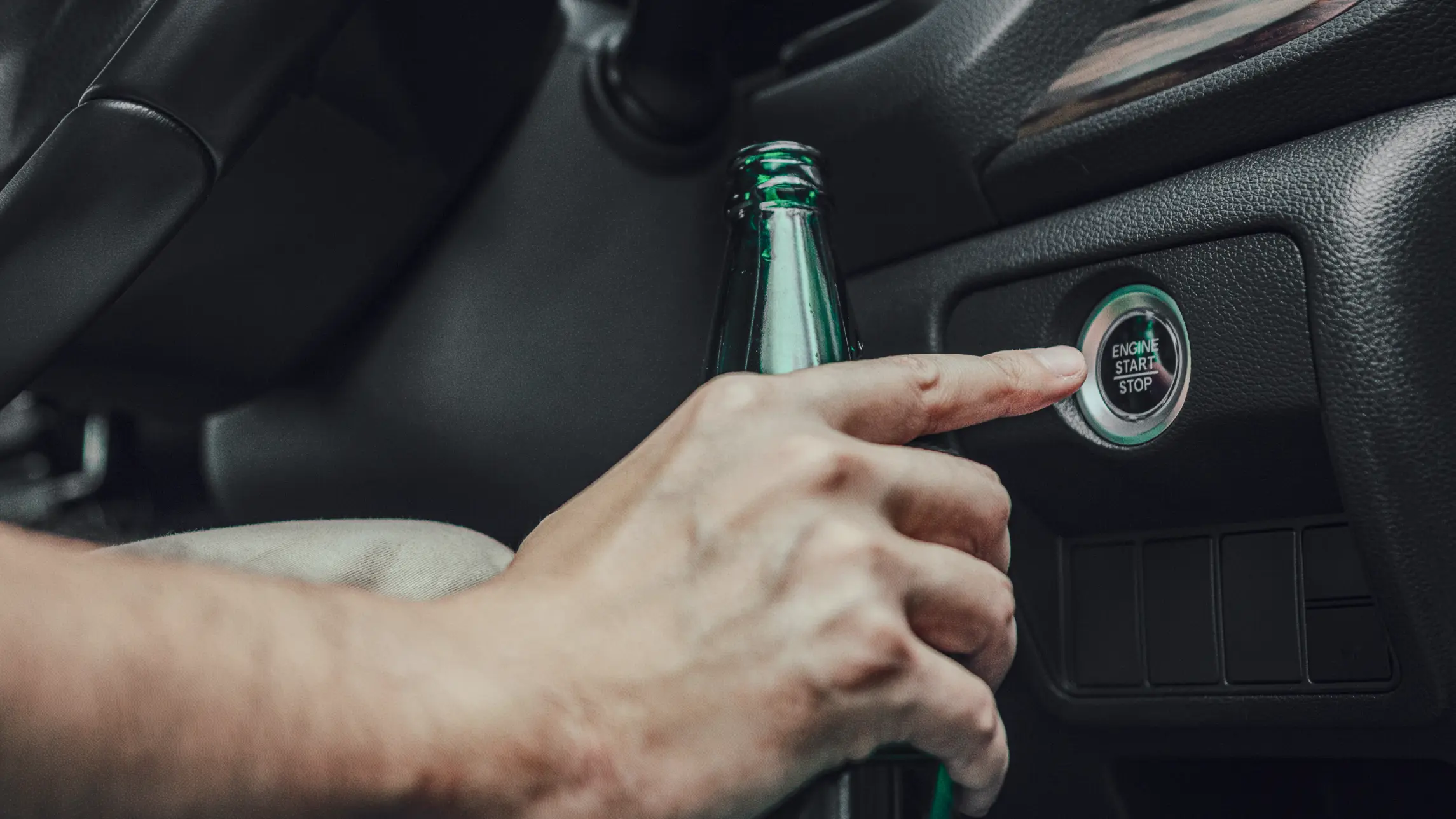 Person with bottle of alcohol in hand starting engine to car