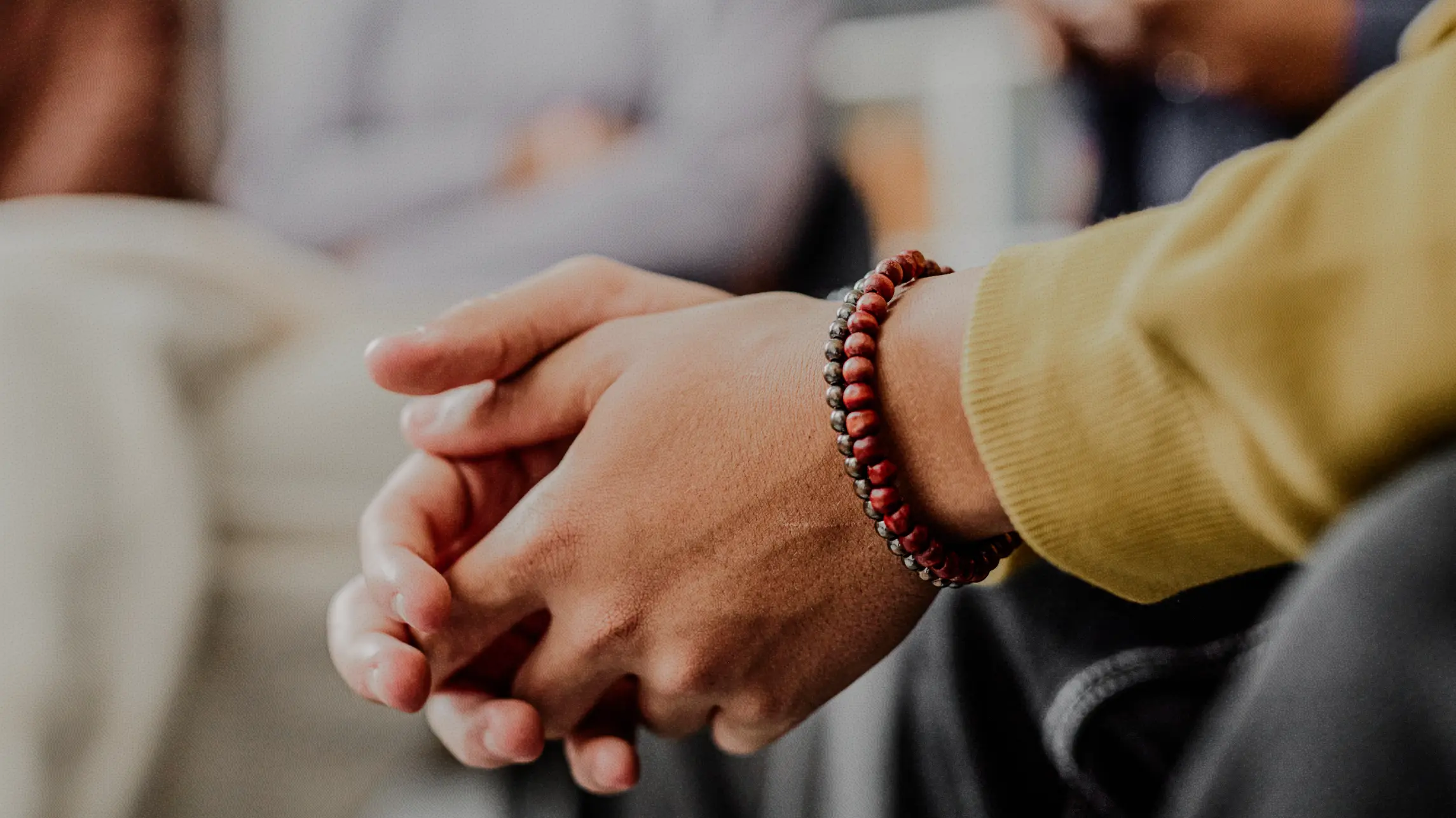 Person holding hands in though in a group setting