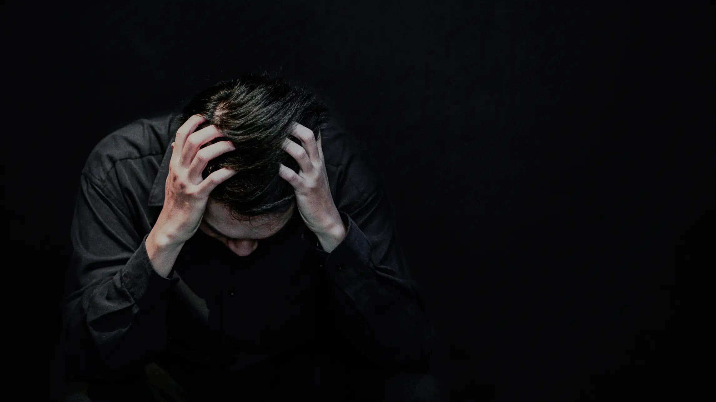 Man distressed sitting in the dark head in hands