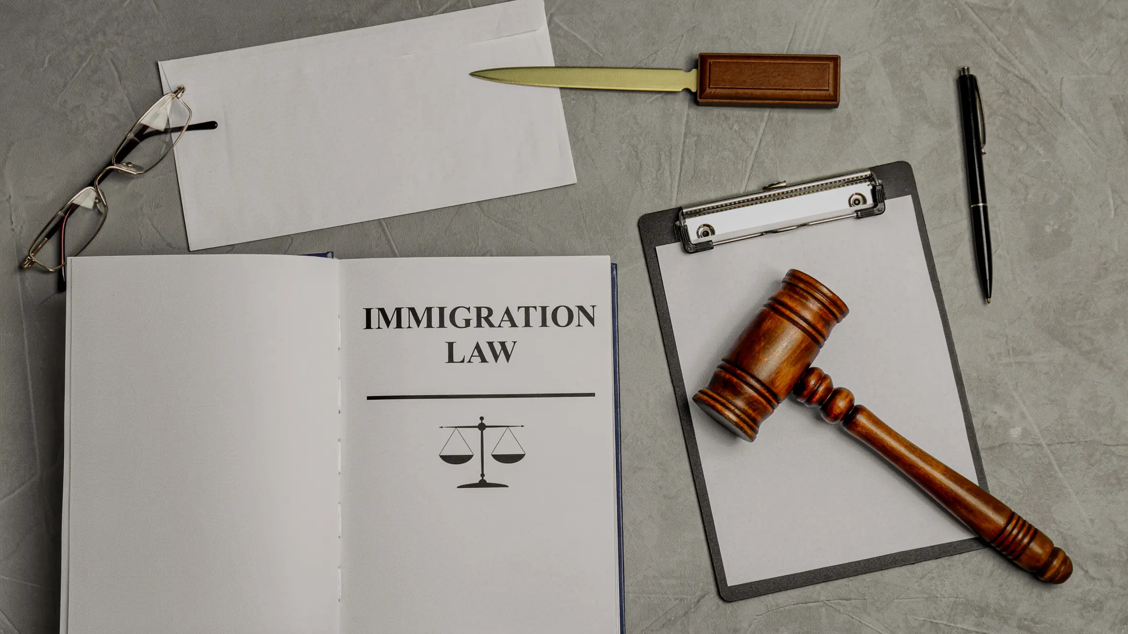Binder with "Immigration Law" on it next to clipboard and judge's gavel