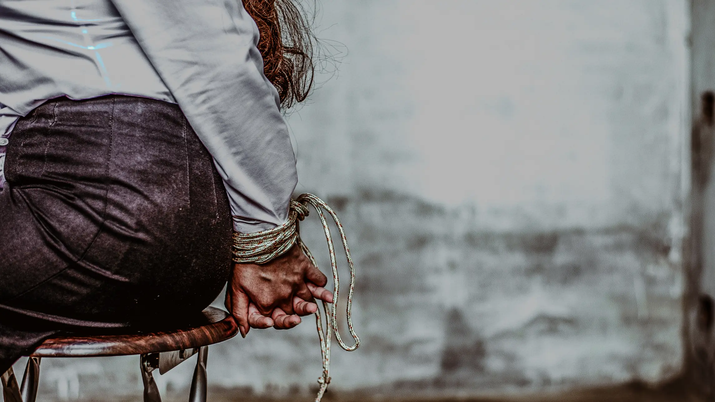 Woman in business clothes tied up in dirty warehouse
