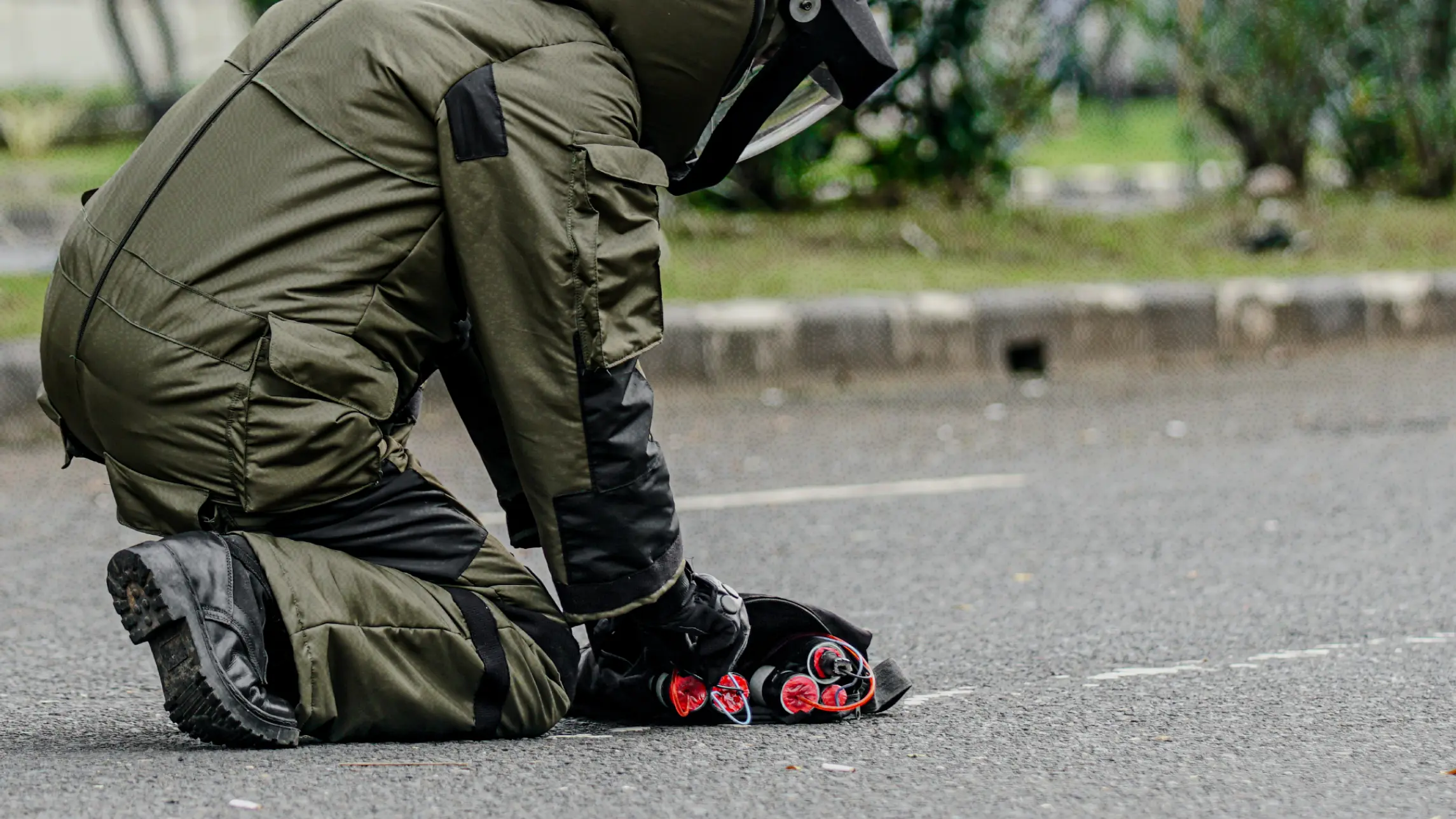 Person in safety suit detonating bomb threat in street