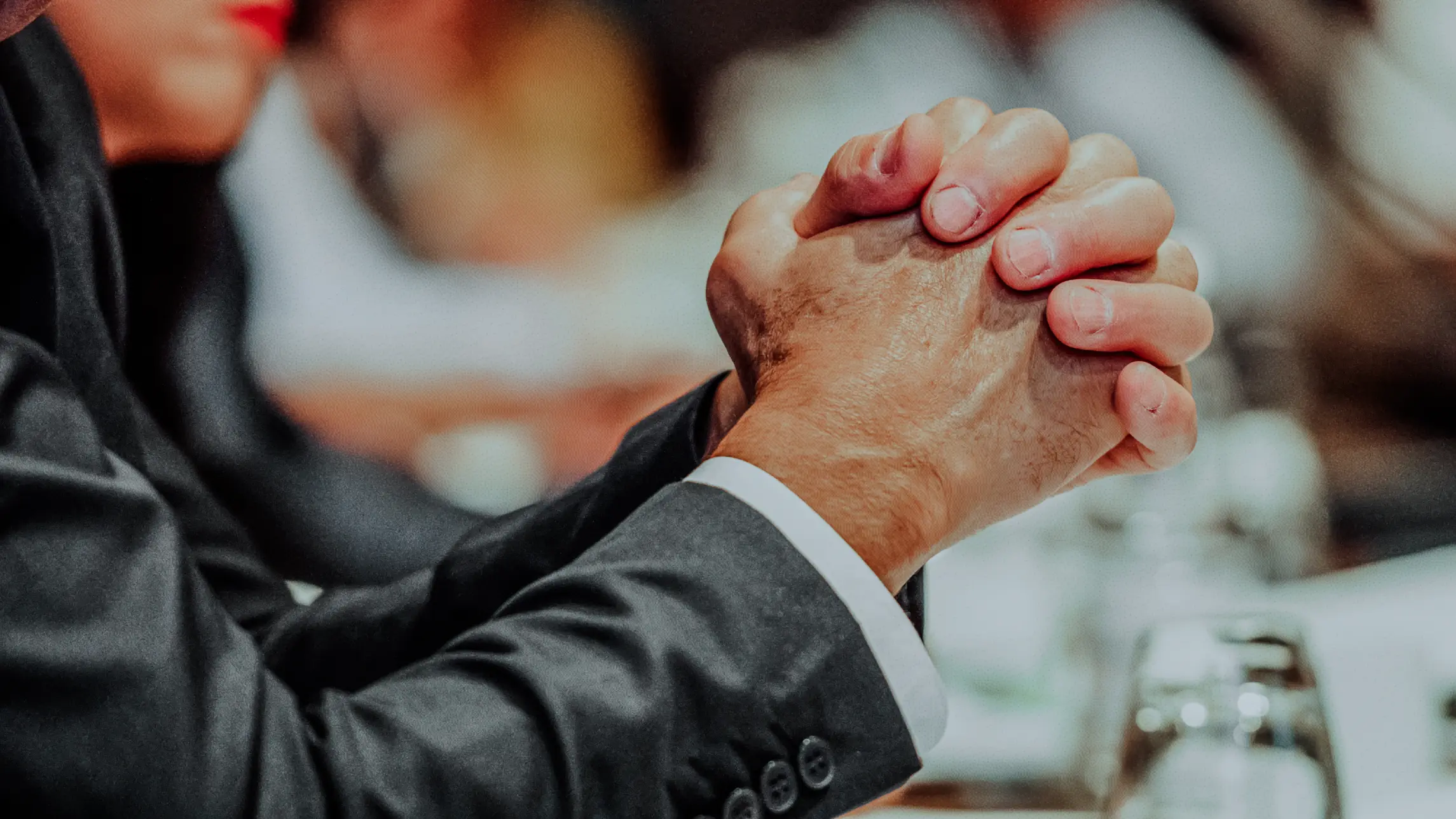 Man folding hands resting on table in courtroom