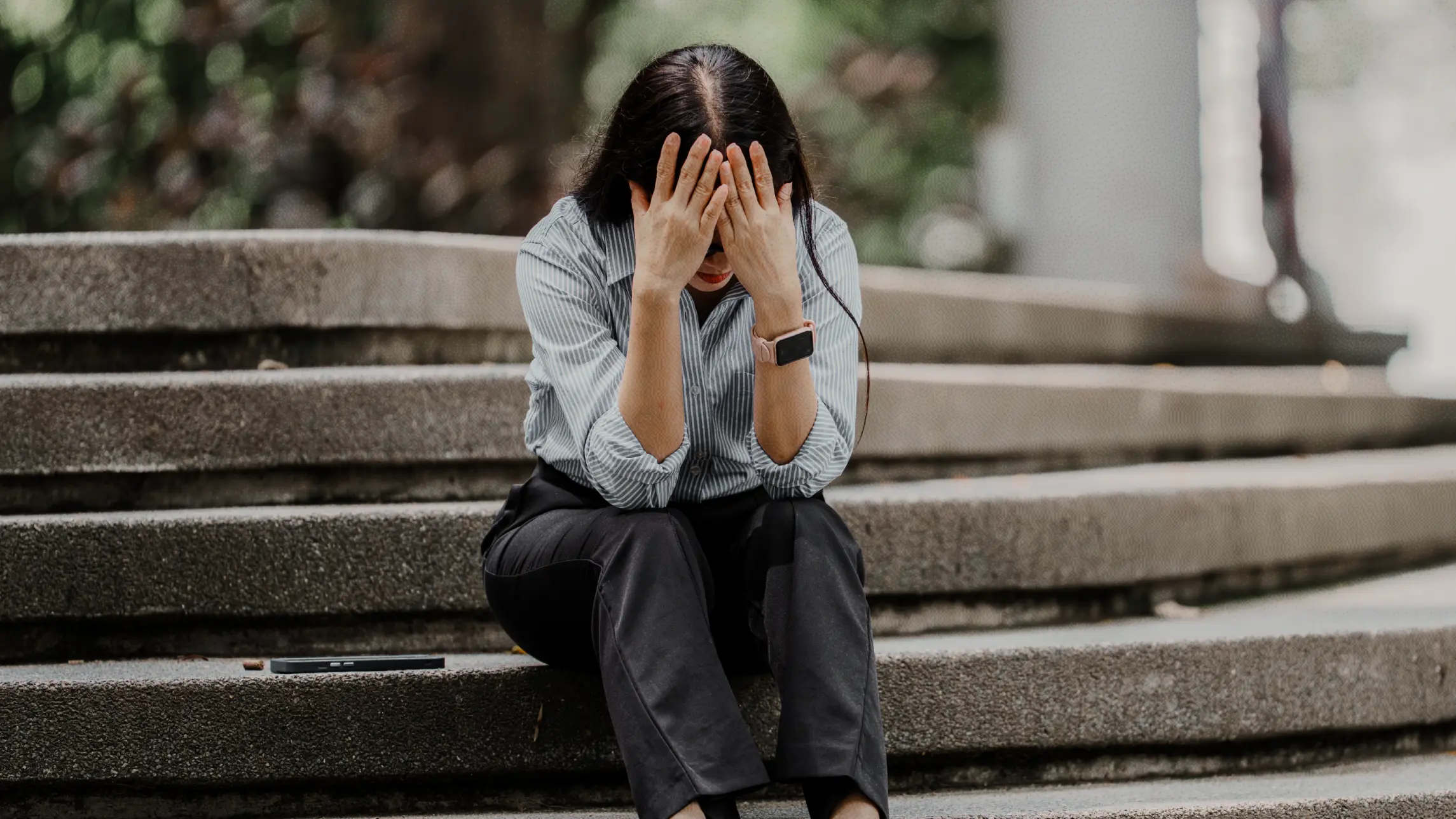 Woman sitting on steps outside with head in hands
