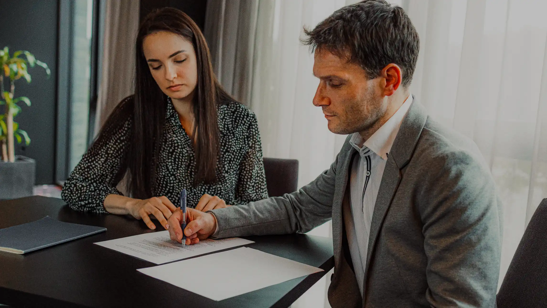 Man signing bail bond application in office with wife