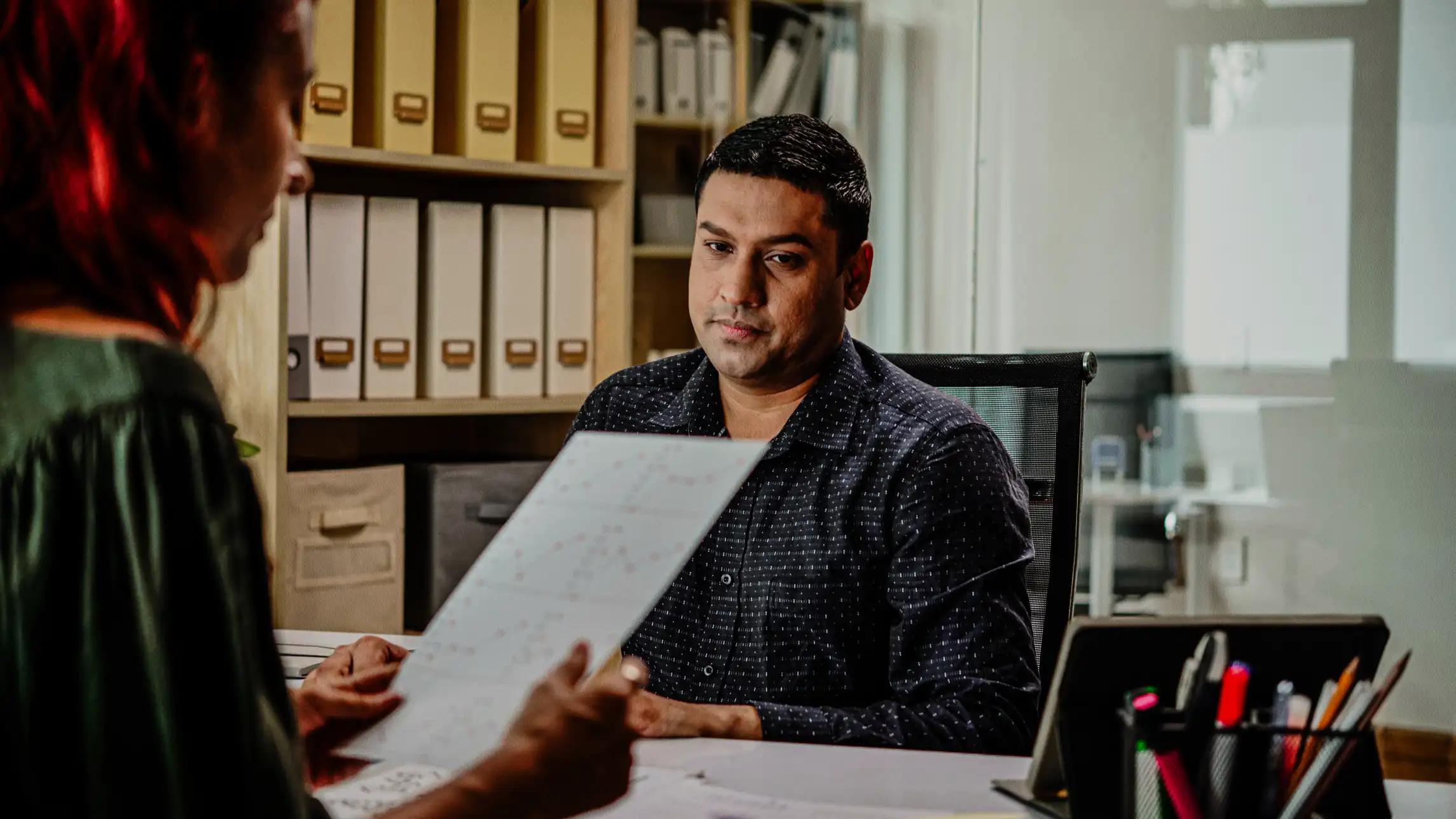 Woman reviewing man's paperwork in office