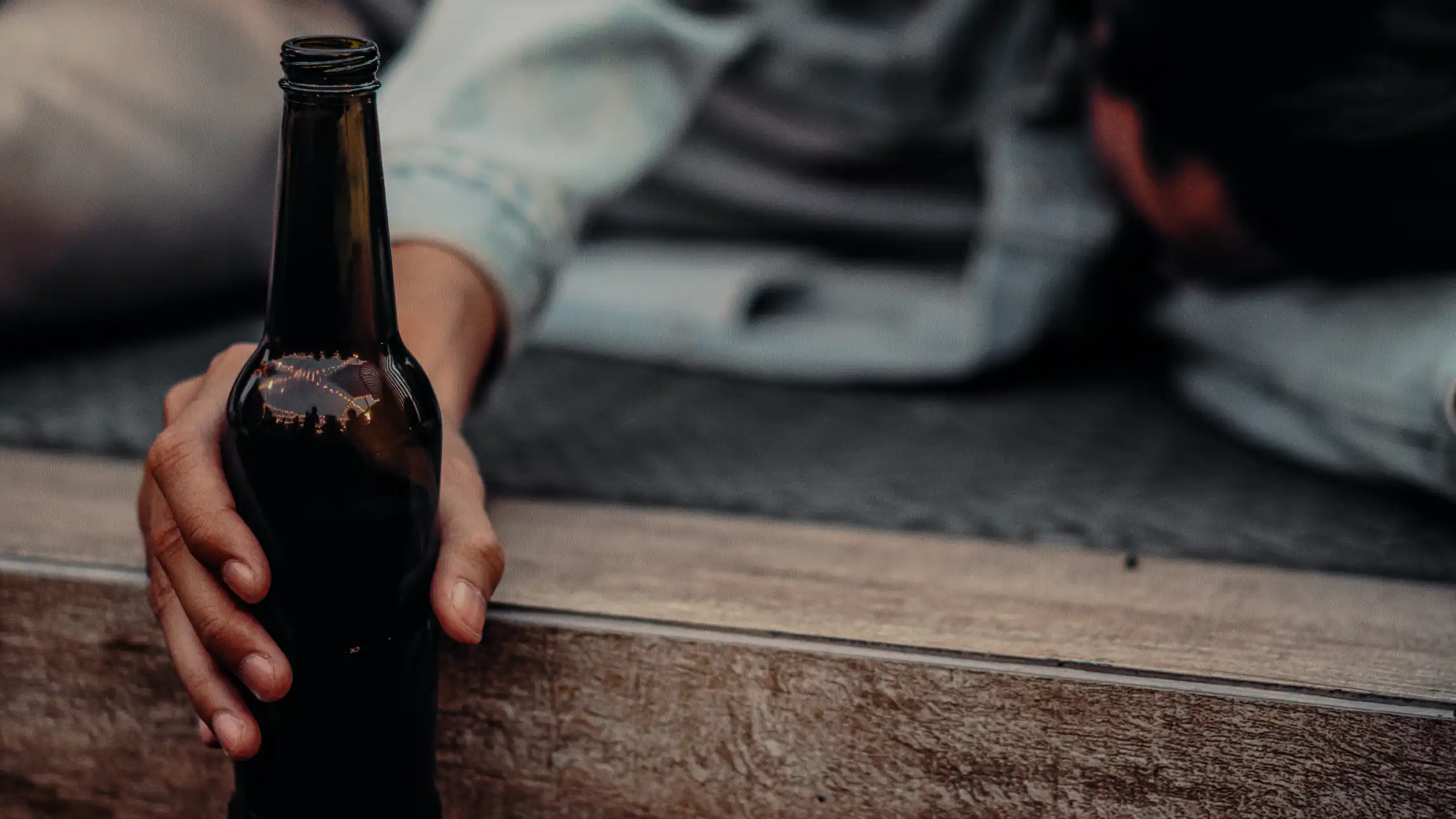Person passed out from drinking clutching beer bottle