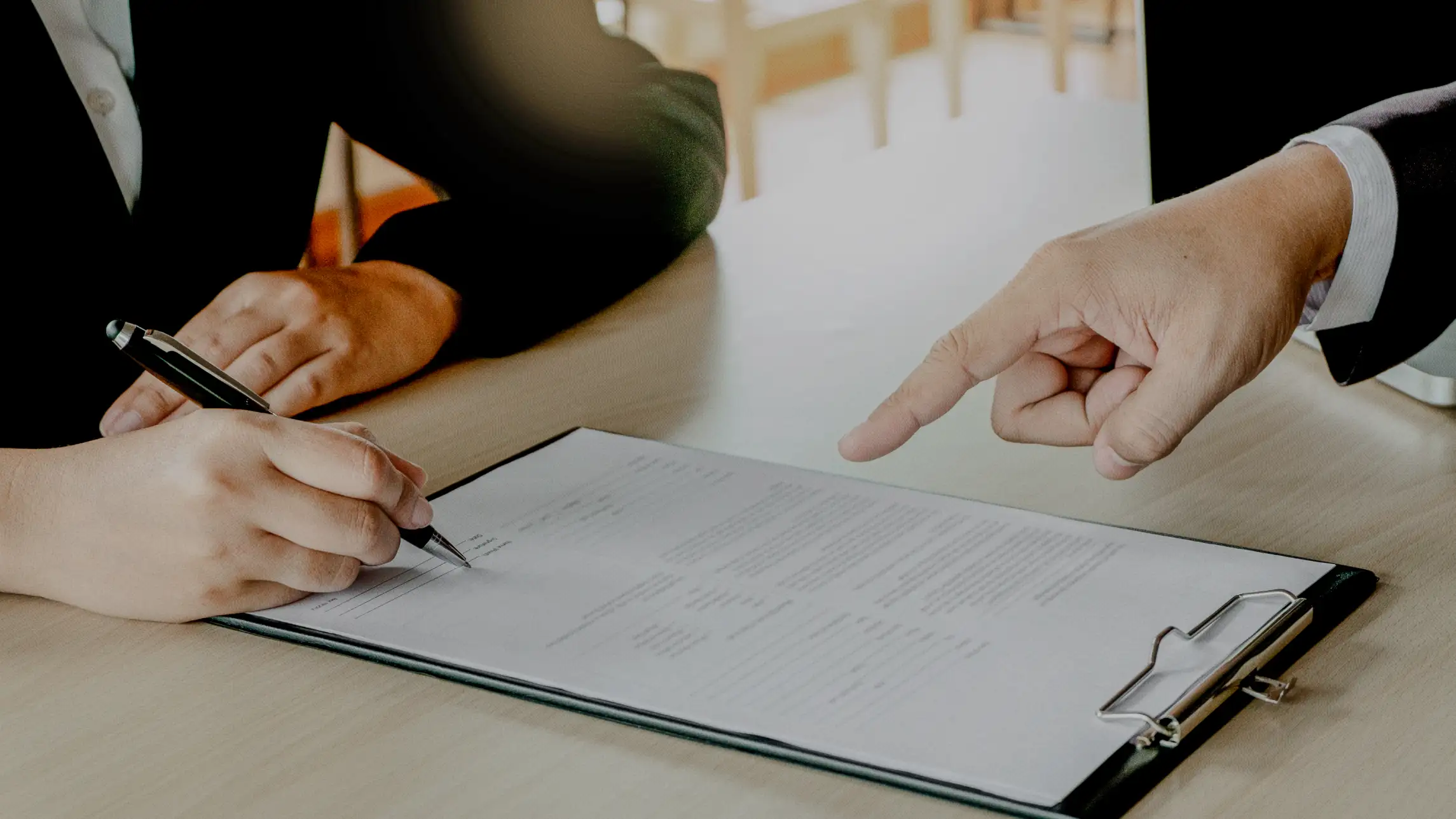 Woman signing name on paperwork with bail agent